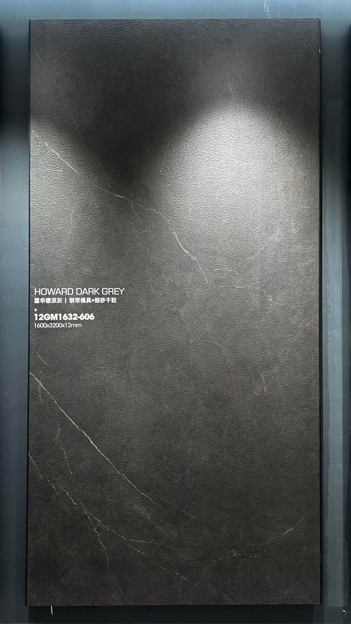 Dalle en pierre frittée gris foncé aux discrètes veines claires dans un cadre en salle d’exposition