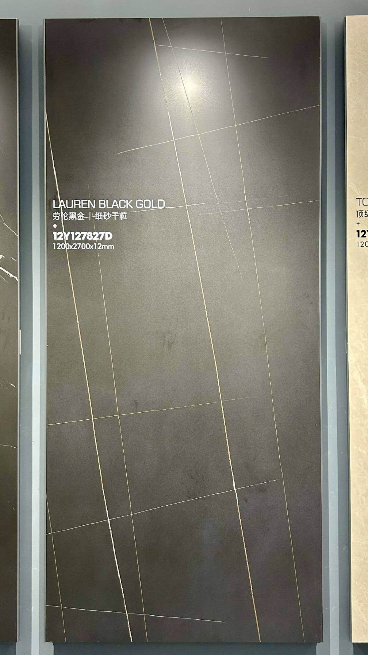Dark slab with fine intersecting gold-toned lines in a showroom frame — Laurent Black Gold Marble Look sintered stone