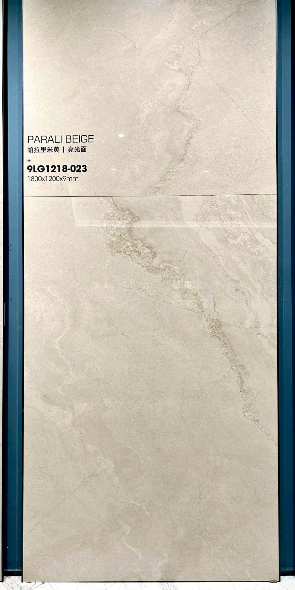 Pale beige sintered stone slab with cloudy grey patches in a showroom frame