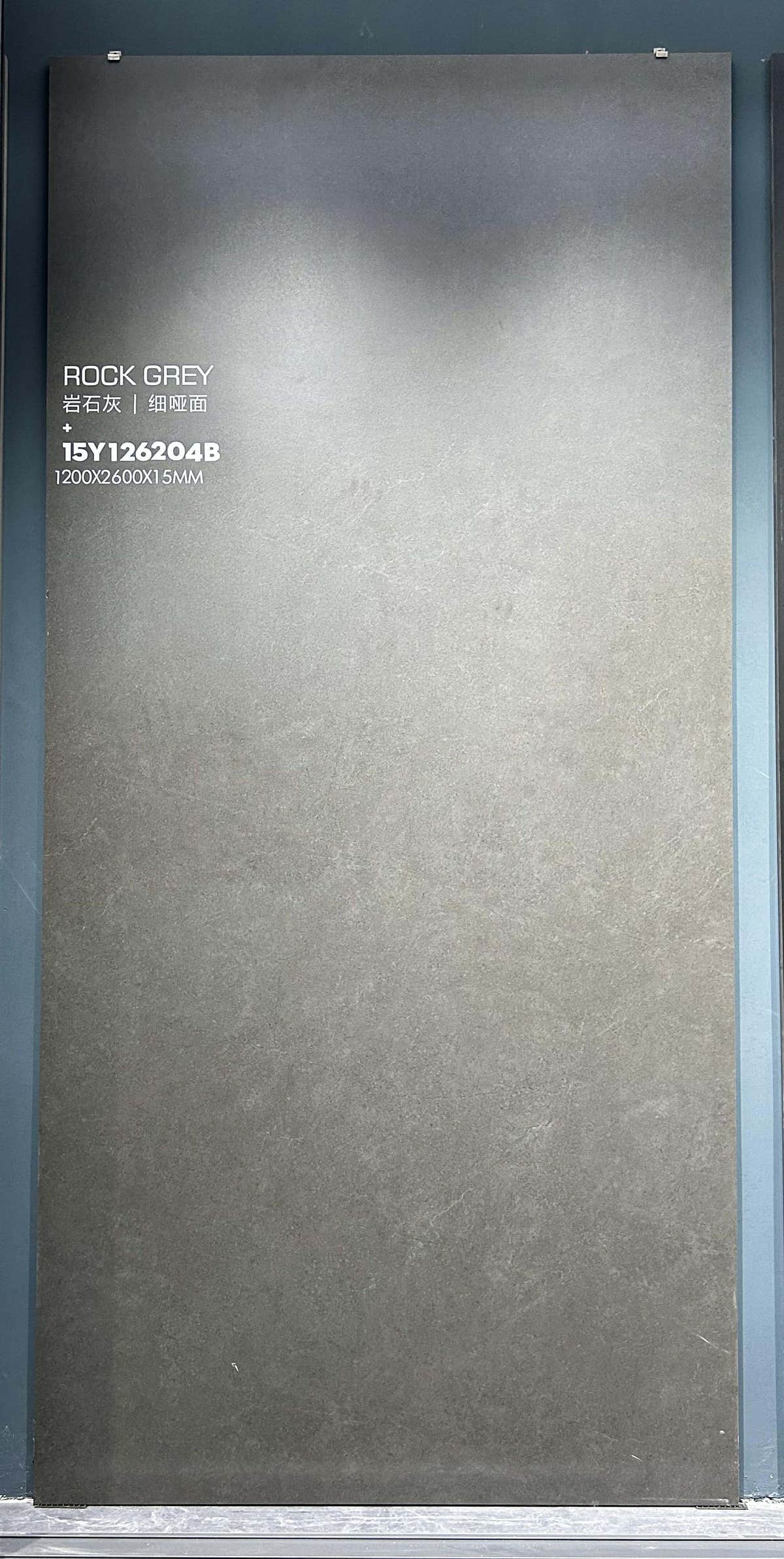 Grey slab with fine mottled texture and faint pale veins on a showroom rack — Rock Grey sintered stone