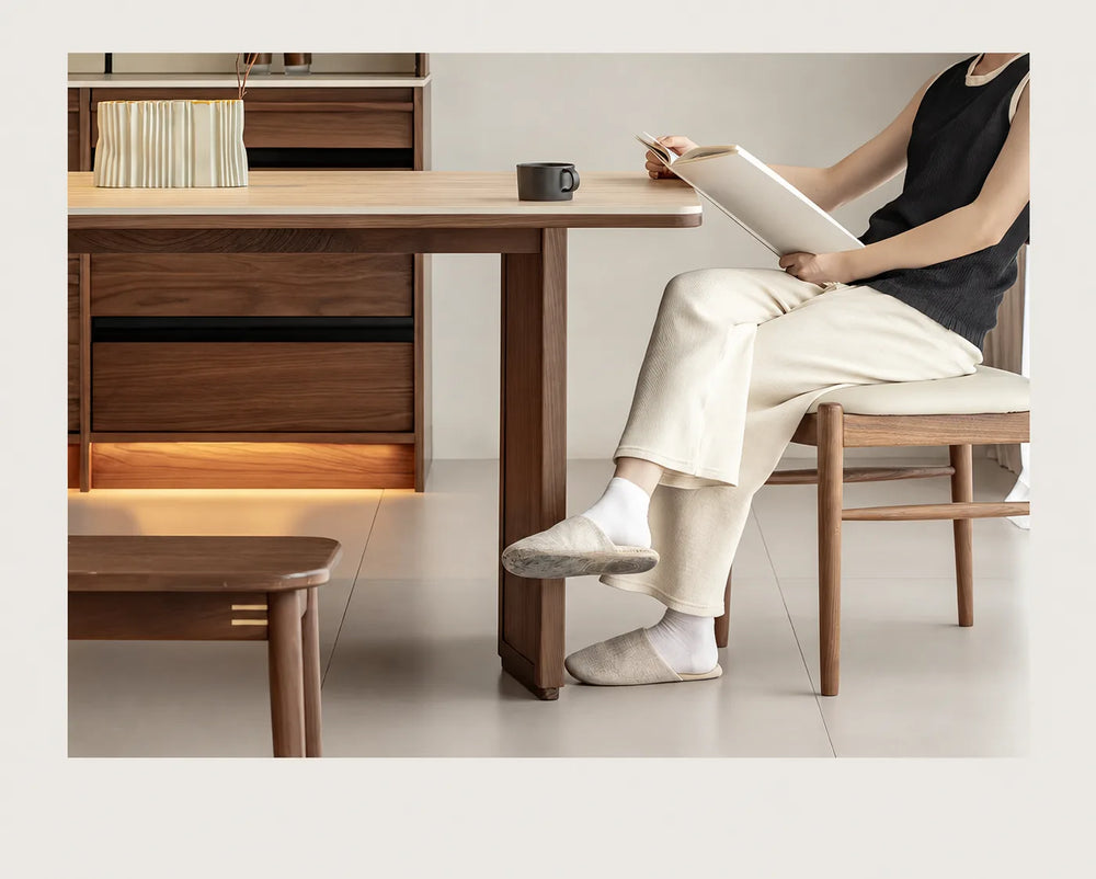 Person reading at a walnut office desk with a pale sintered stone top