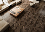 Sol de salon sombre à motif géométrique effet bois autour d’assises claires — pierre frittée Dark Shipwood Geometric Wood Look