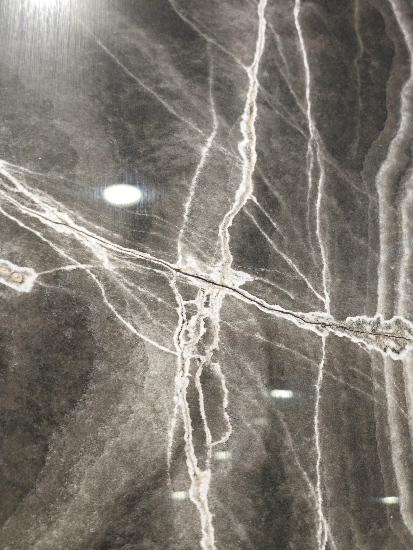 Polished black stone surface with intersecting white mineral fractures