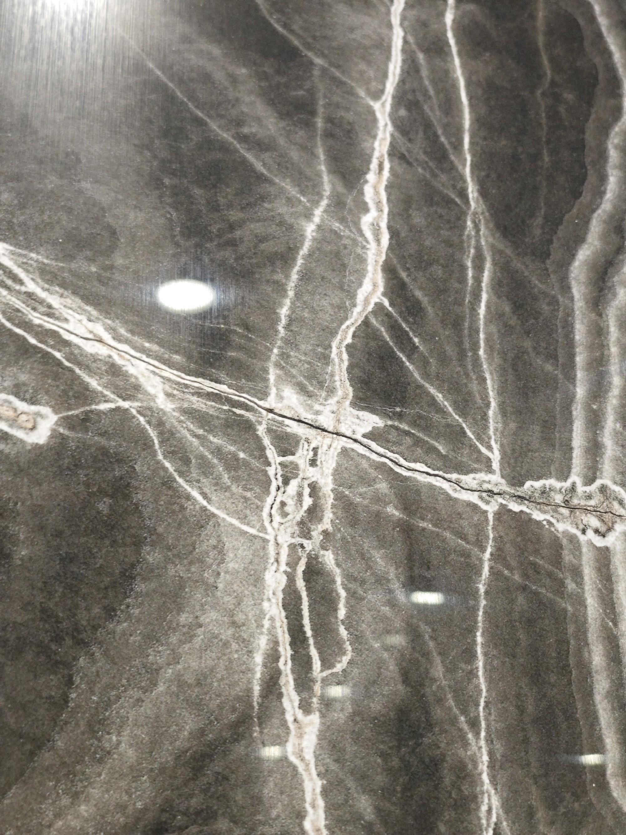 Polished black stone surface with intersecting white mineral fractures