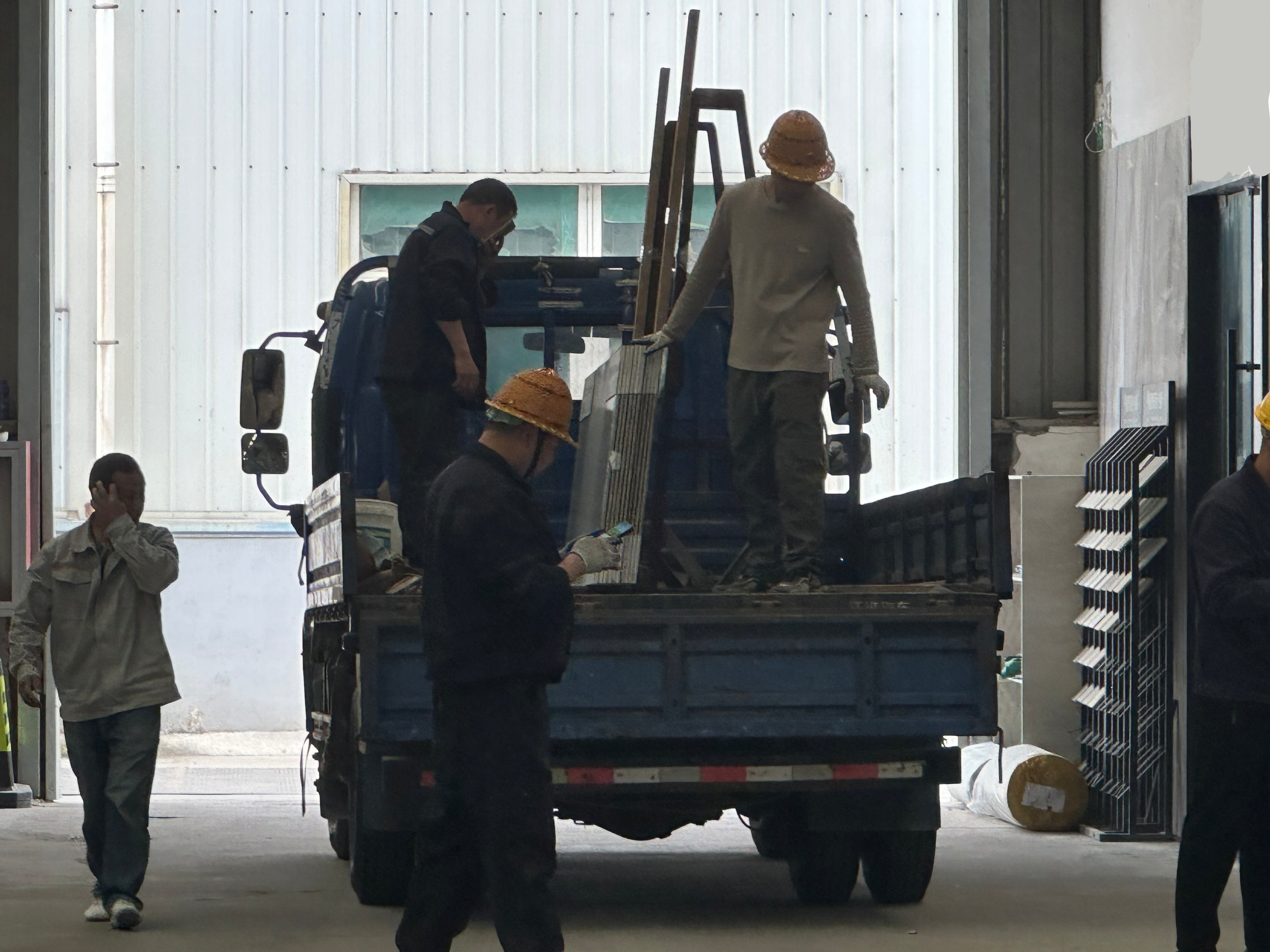 Workers loading large sintered stone slabs onto truck in warehouse