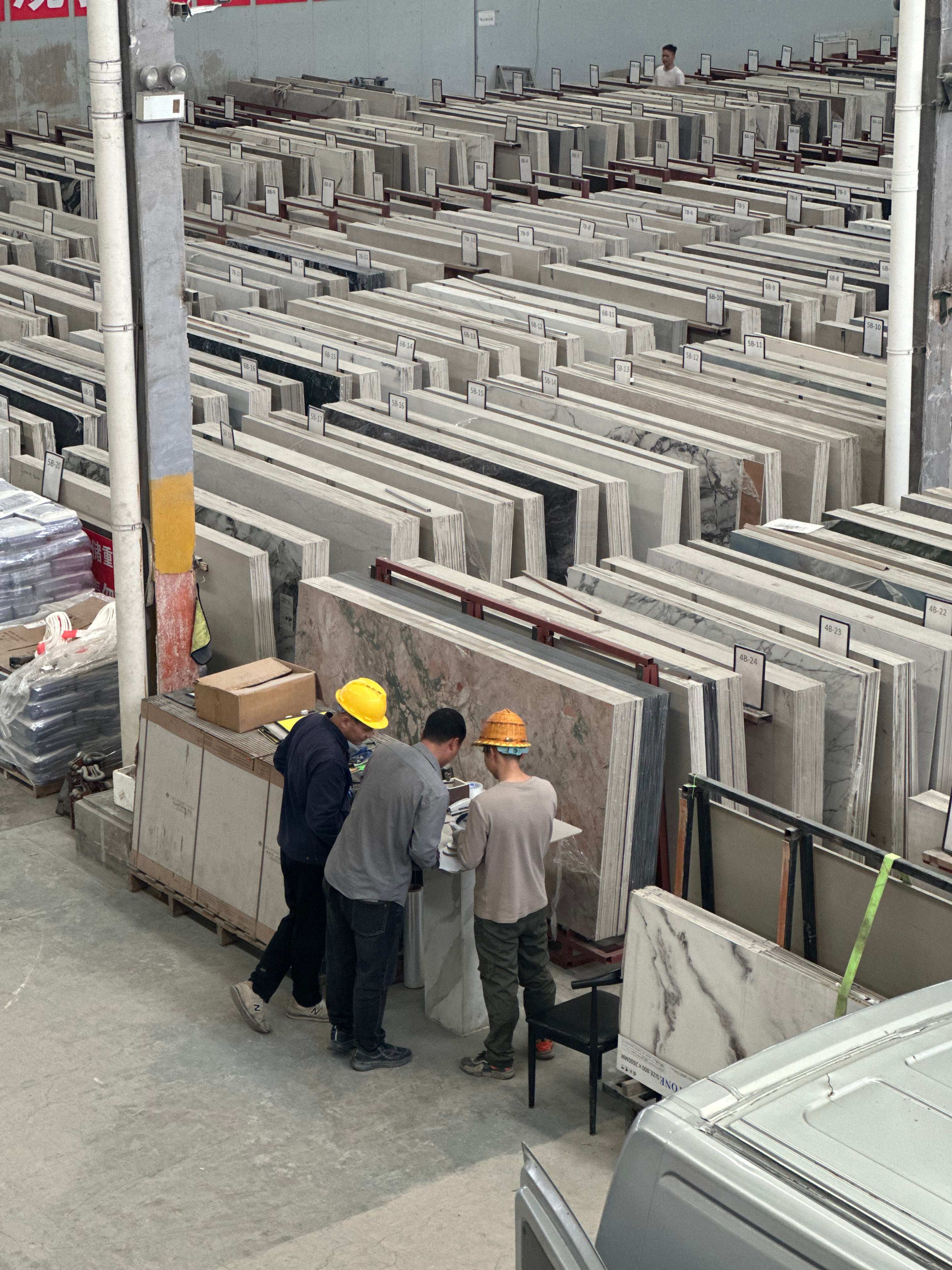 Workers inspecting large sintered stone slabs in warehouse