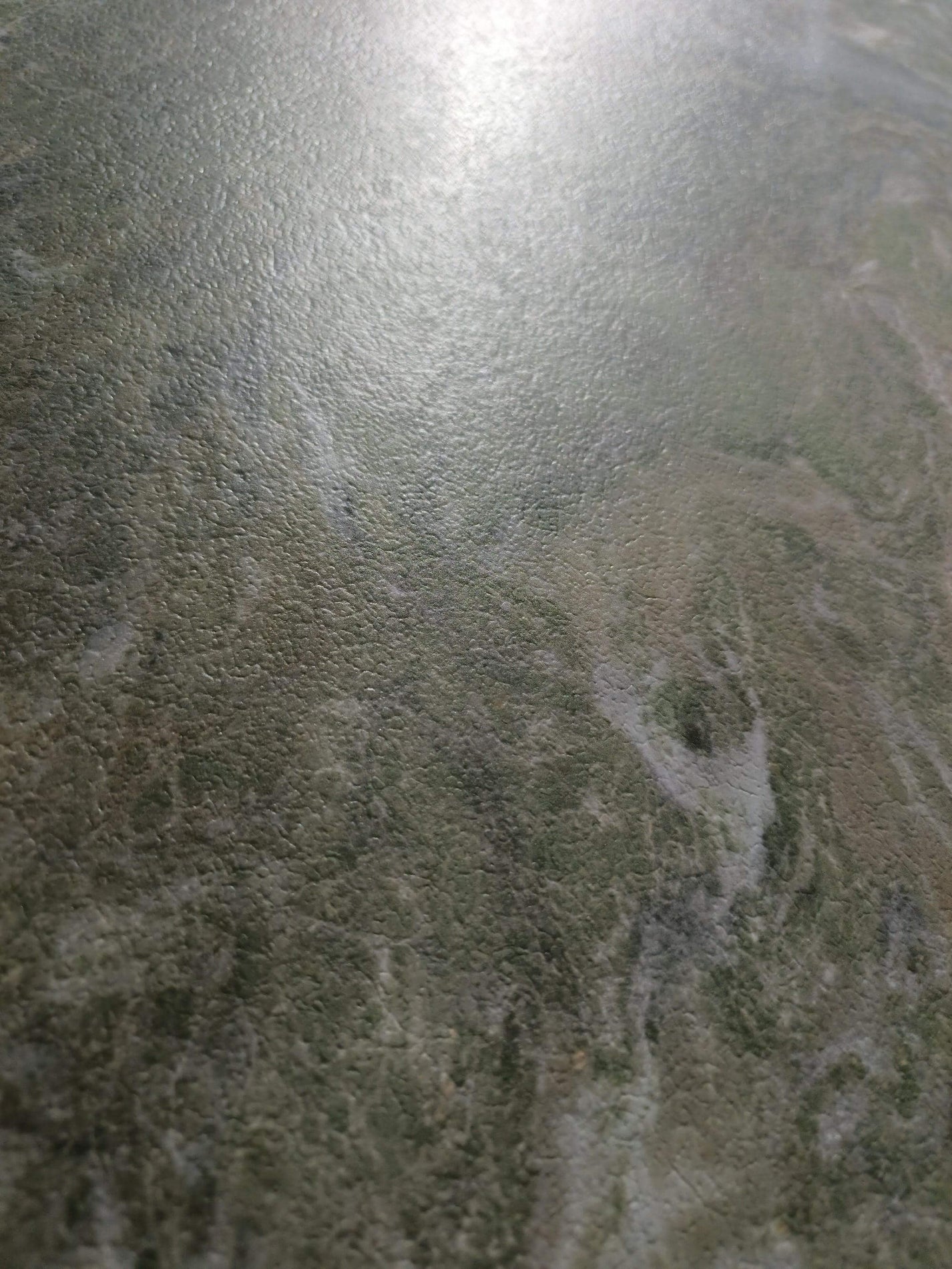 Close detail of the fine embossed texture over muted sage mineral clouds