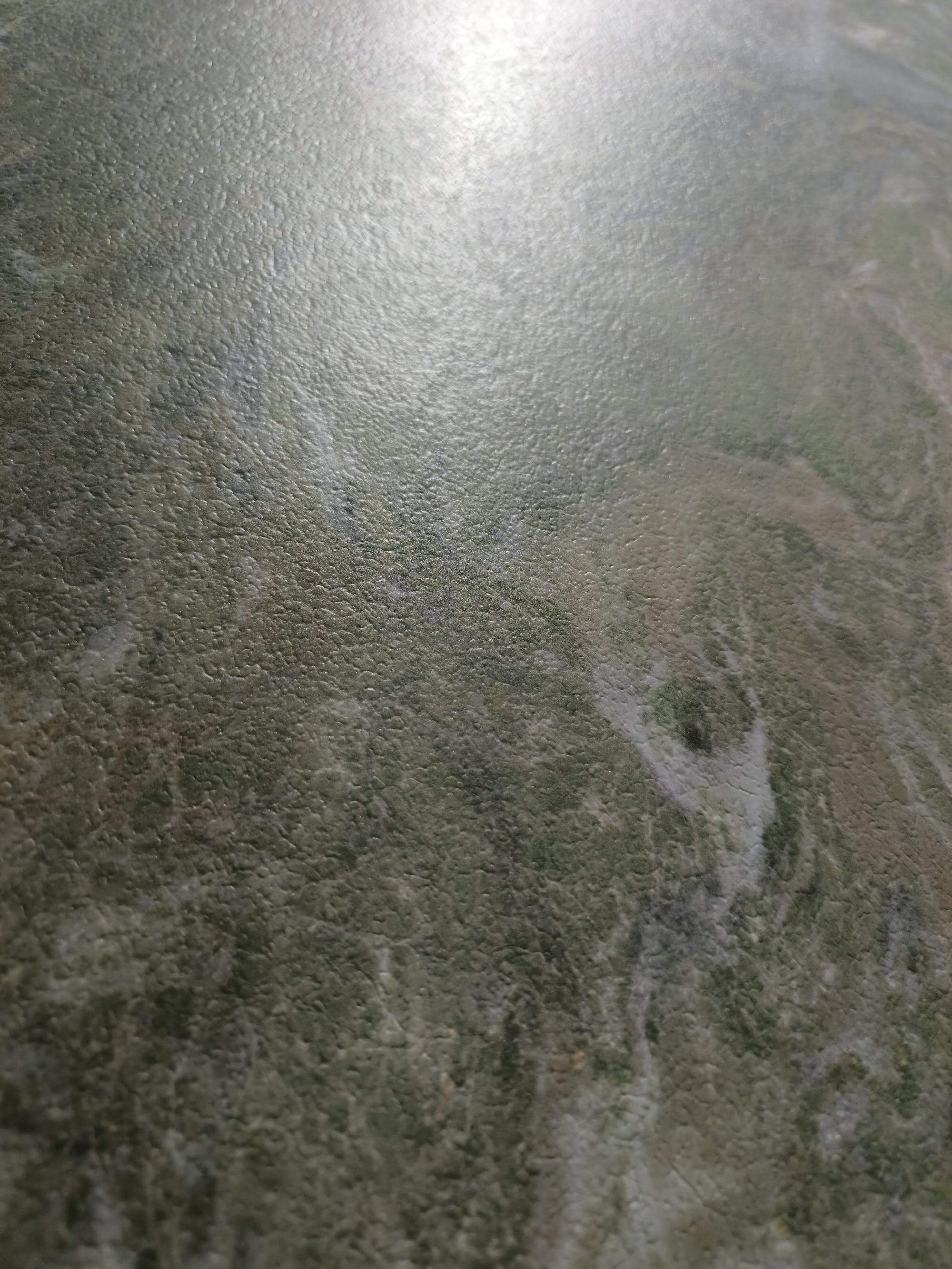 Close detail of the fine embossed texture over muted sage mineral clouds