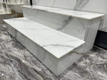 Expositor escalonado con vetas blancas y grises que muestra peldaños horizontales y caras verticales: piedra sinterizada Libes White Breccia Look