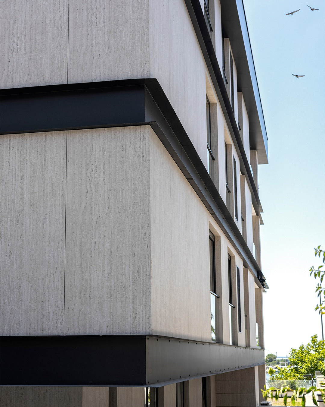 Modern architectural facade featuring large-format beige travertine-look sintered stone panels for exterior wall cladding.
